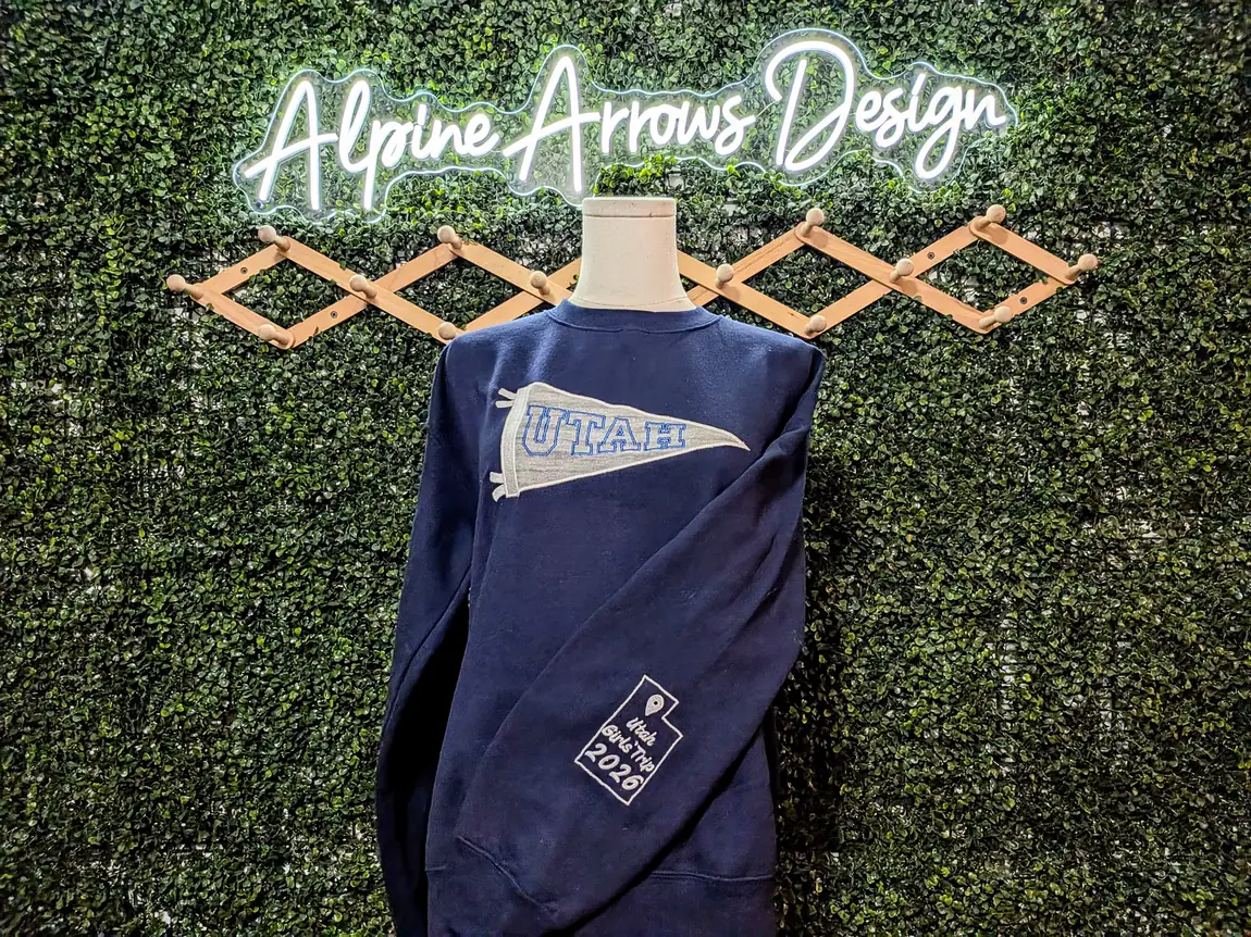 Navy sweatshirt with an applique felt pennant on the chest and a custom embroidered sleeve design