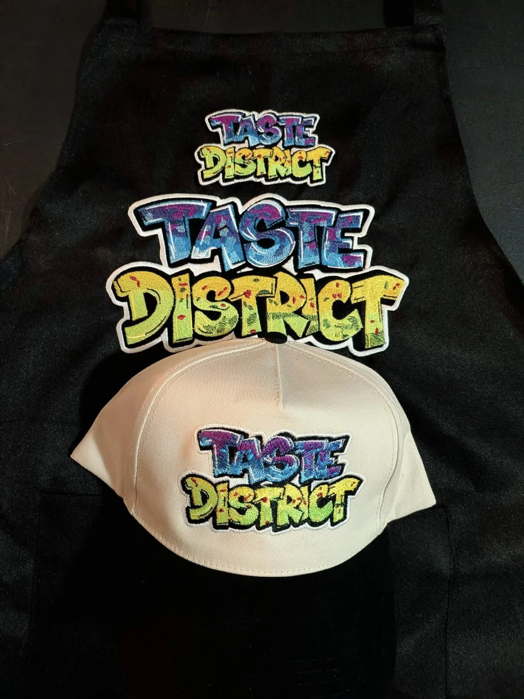 Custom embroidered patches stitched in-house and applied to a work apron and cap