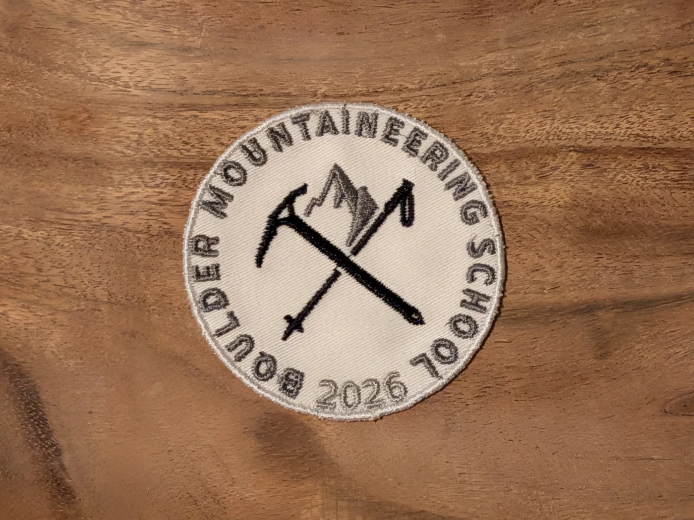 Custom embroidered mountaineering school patch with crossed ice axes and a merrowed border