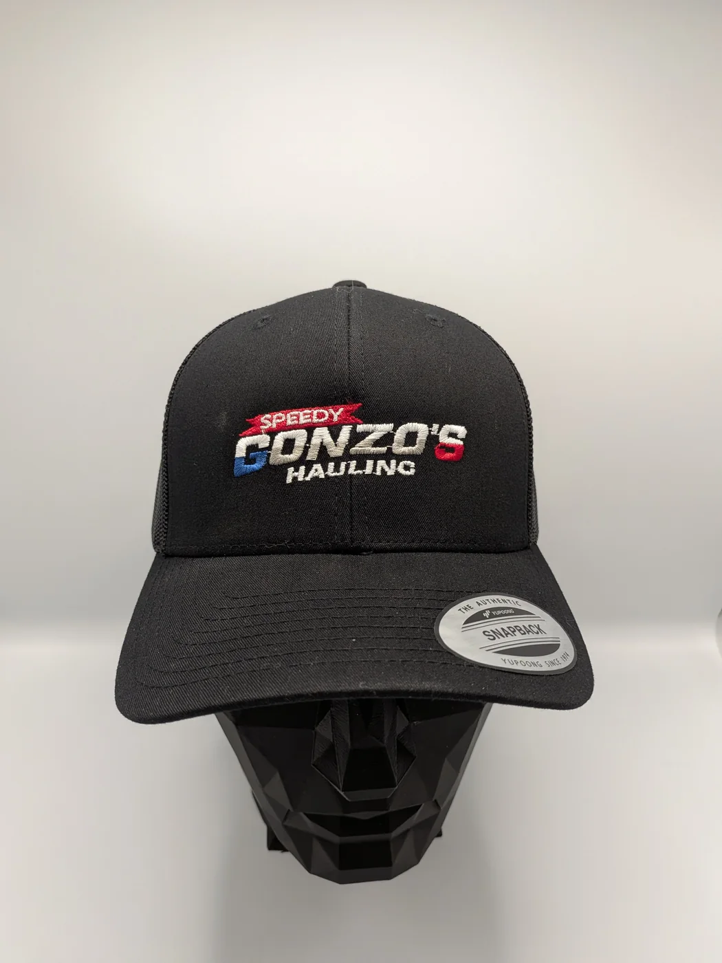 Black cap with a multi-color embroidered hauling company logo stitched in red, white and blue thread